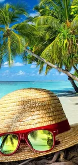 Straw hat and sunglasses on a tropical beach with palm trees.