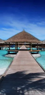 Tropical beach with pier and thatched huts under a clear blue sky.