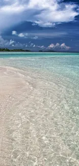 Serene beach with clear water and dramatic clouds in the sky.