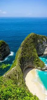 Tropical beach with cliffs and ocean waves under a clear blue sky.