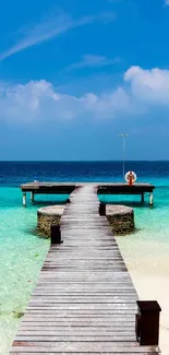 Tropical pier on beach under vibrant blue sky.