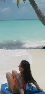 A woman relaxes under a palm tree on a turquoise beach.