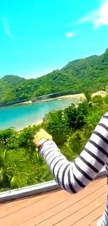 Woman looks over tropical beach with lush hills and blue sky.