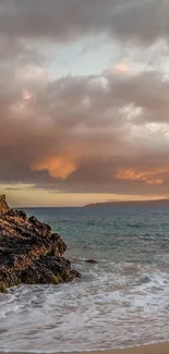 Tropical beach at sunset with palm trees, rocks, and ocean waves.