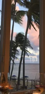 Tropical beach view through a window with palm trees at sunset.