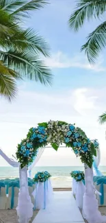 Tropical beach wedding with floral arch under palm trees and clear blue sky.