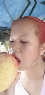 Woman enjoying a large mango with a blue sky background.