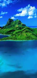 Tropical island with blue ocean and lush green hills under a clear sky.