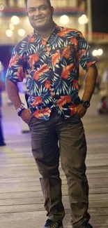 Man in a floral shirt on a boardwalk at night, vibrant tropical theme.