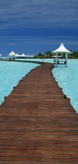 Tropical boardwalk leading over clear aqua water under a blue sky.