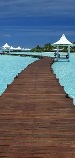 Wooden pier leading into vibrant blue ocean under blue sky with white gazebos.