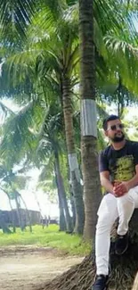 Man sitting under tropical palm trees in a lush green setting.