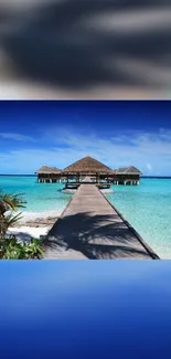 Tropical beachfront with turquoise sea and wooden pier under clear sky.