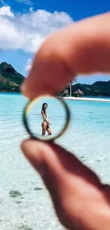 Tropical beach scene framed through a ring in hand.