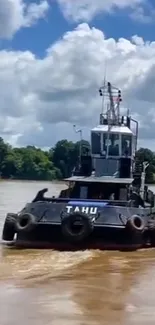 Tugboat navigating a calm river with lush greenery and a cloudy sky.