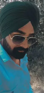 Man in dark green turban and sunglasses in a natural setting.