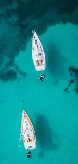 Two sailboats on a turquoise sea from above, offering tranquility.