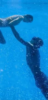 Two swimmers in a tranquil underwater scene with clear blue water.