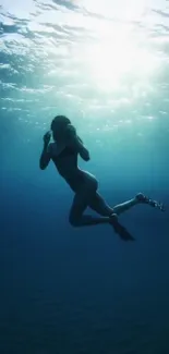 Serene underwater wallpaper with swimmer in deep blue hues.