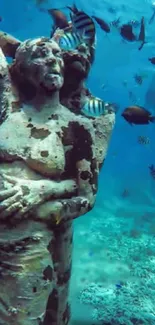 Underwater statue with fish swimming around in a serene blue ocean.