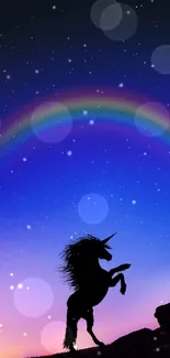 Silhouette of a unicorn under a vibrant night sky with a rainbow.