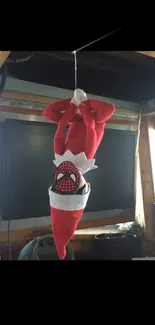 Upside-down Santa elf with superhero theme hanging as decoration.