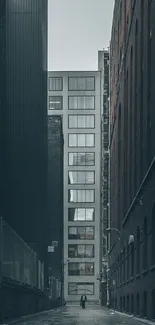 Narrow alley between tall urban buildings with a person walking down the path.