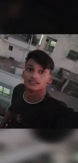 Young individual on balcony with city view at dusk.