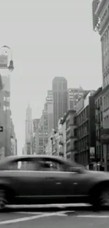 Black and white cityscape with moving car and tall buildings.