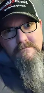 Urban casual portrait of a bearded man with glasses and a hat.