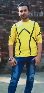 Person in urban style with a yellow sweater against a brick wall.