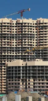 High-rise building under construction with cranes against a blue sky.