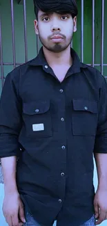 Young man in black shirt standing outdoors, urban style.