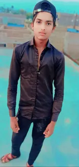 Young man standing on rooftop with blue city backdrop.