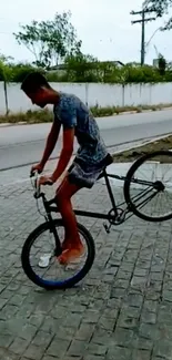 Cyclist performs a bicycle stunt on a cobblestone street.