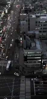 Arial view of city streets at night with illuminated buildings and traffic.