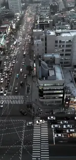 Aerial view of city street in the evening, with cars and buildings illuminated by lights.