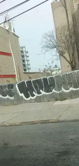 A city street with bold graffiti art on a gray fence.