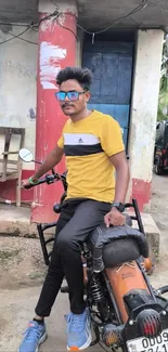 Man in yellow shirt sitting on a motorcycle in urban setting.