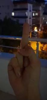 Hand showing gesture against urban night scenery.