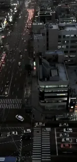 Aerial view of an urban street at night with vibrant city lights and traffic.