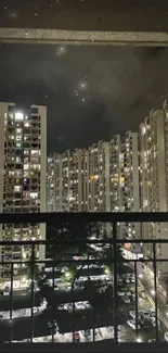 Night view of city skyline from a high-rise balcony, illuminated by city lights.