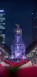 Illuminated statue on urban night street with skyscrapers.