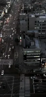 Aerial nighttime city view with traffic and illuminated buildings.