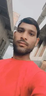 Selfie in red shirt amidst urban architecture.