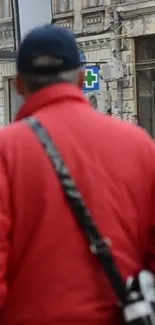 Person in red jacket walking in urban street.