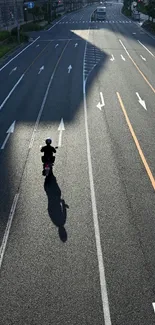 Cyclist on empty urban road casting a long shadow.