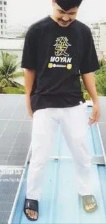 Person on rooftop in black t-shirt and white pants with solar panels.