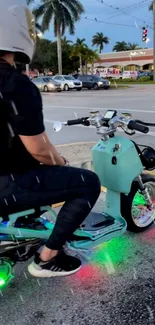 Person on a scooter at a city intersection with vibrant lights.