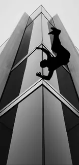 Silhouette of a figure scaling a modern building in monochrome.